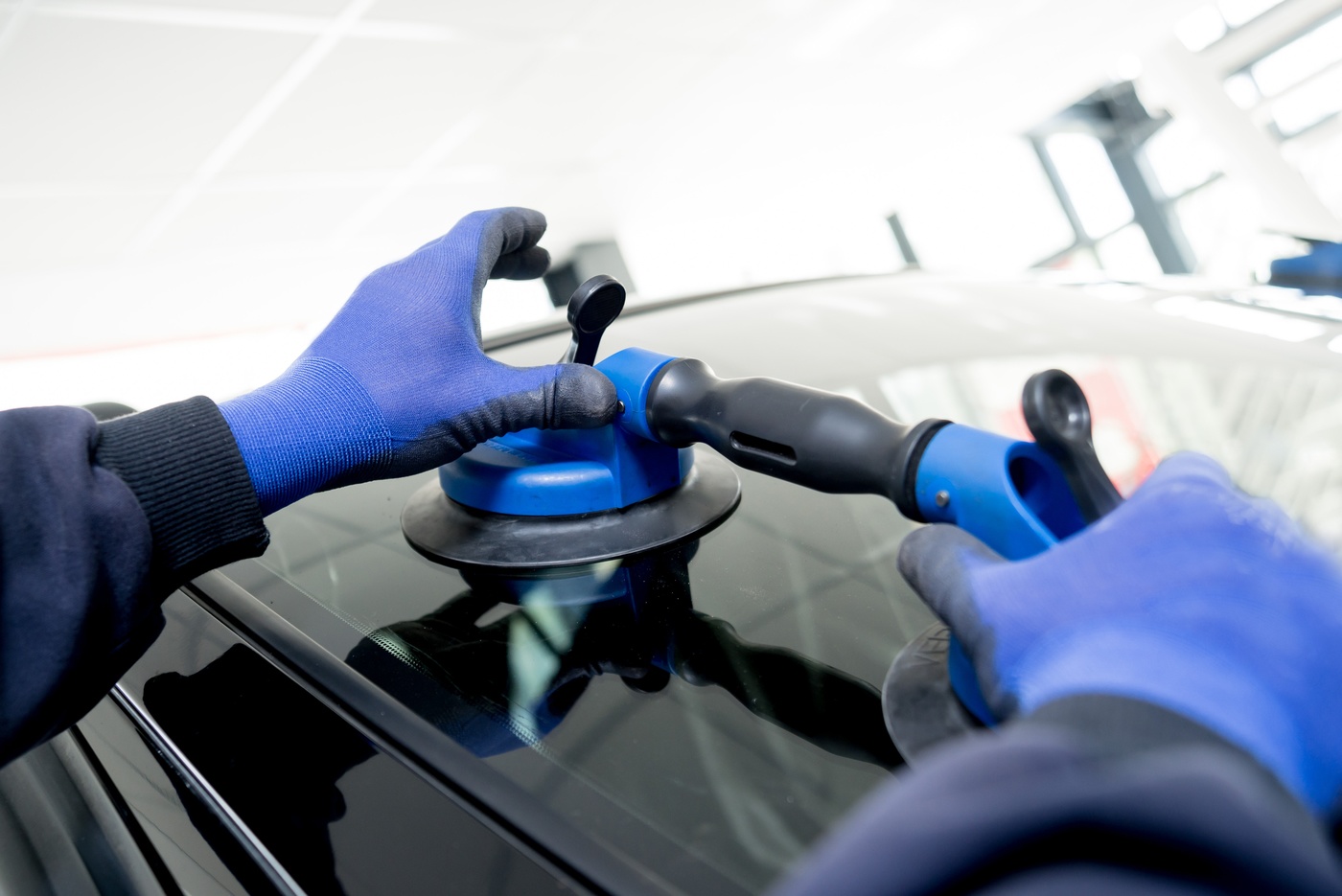 Experienced technician performing auto glass replacement on a vehicle windshield.